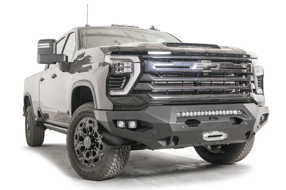 Fab Fours Matrix front bumper on a black Chevrolet Silverado 2500HD, front passenger-side three-quarter view, showing the no-guard design, integrated light bar and winch fairlead