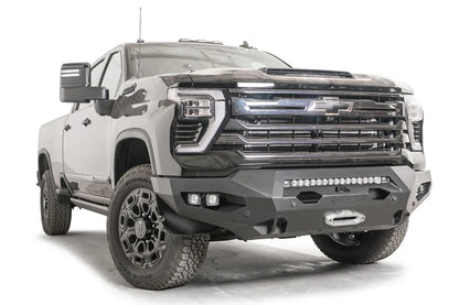 Fab Fours Matrix front bumper on a black Chevrolet Silverado 2500HD, front passenger-side three-quarter view, showing the no-guard design, integrated light bar and winch fairlead