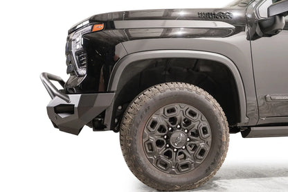 Fab Fours Matrix front bumper with pre-runner guard on a black Chevrolet Silverado 2500HD, side close-up of the front corner, showing the pre-runner tube, bumper end wing and wheel clearance