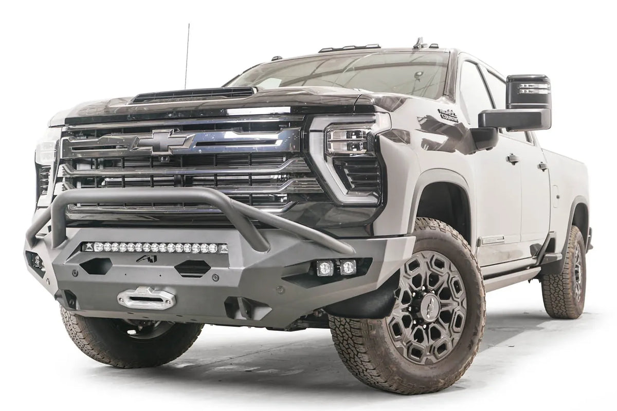 Fab Fours Matrix front bumper with pre-runner guard on a black Chevrolet Silverado 2500HD, front driver-side three-quarter view, showing the pre-runner hoop, integrated light bar and pod light openings