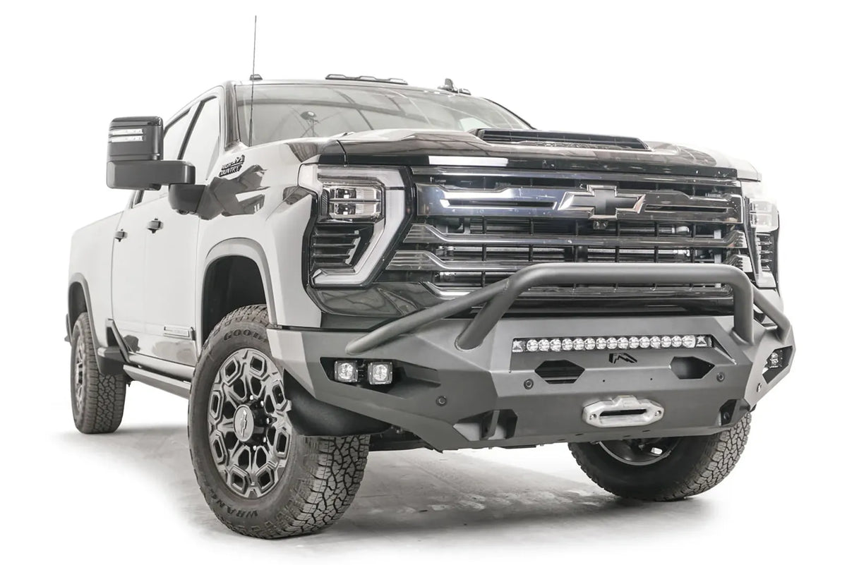 Fab Fours Matrix front bumper with pre-runner guard on a black Chevrolet Silverado 2500HD, front passenger-side three-quarter view, showing the tubular pre-runner hoop, integrated light bar and winch fairlead