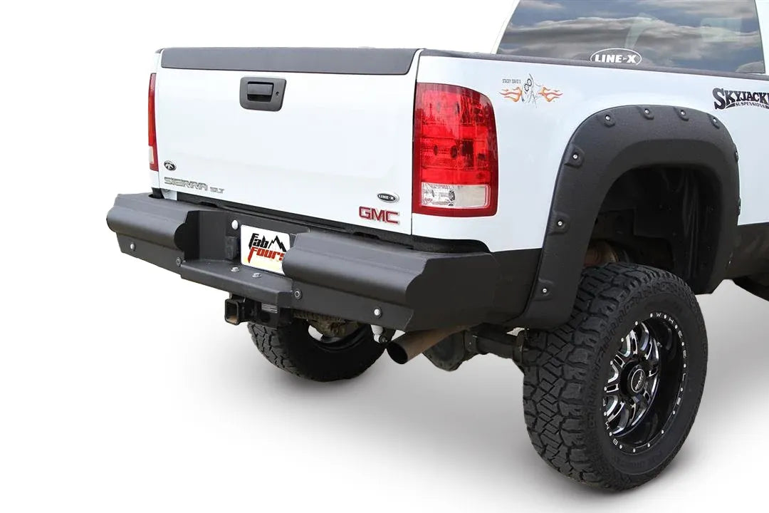 Fab Fours Black Steel Elite rear bumper on a white lifted GMC Sierra, rear passenger-side three-quarter view on a white background, showing the black steel face, wraparound end cap and center hitch receiver