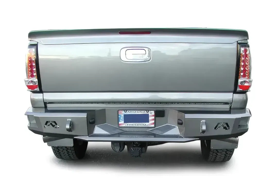 Fab Fours Premium rear bumper on a gray Chevrolet Silverado 2500HD, straight-on rear view, showing the black steel bumper face, logo cutouts, D-ring mounts and center step