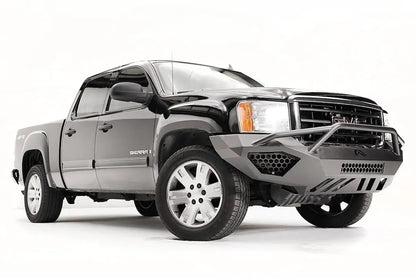 Fab Fours Vengeance front bumper with pre-runner guard on a black GMC Sierra 1500, front passenger-side three-quarter view, showing the pre-runner hoop, honeycomb mesh vent and angular end wing