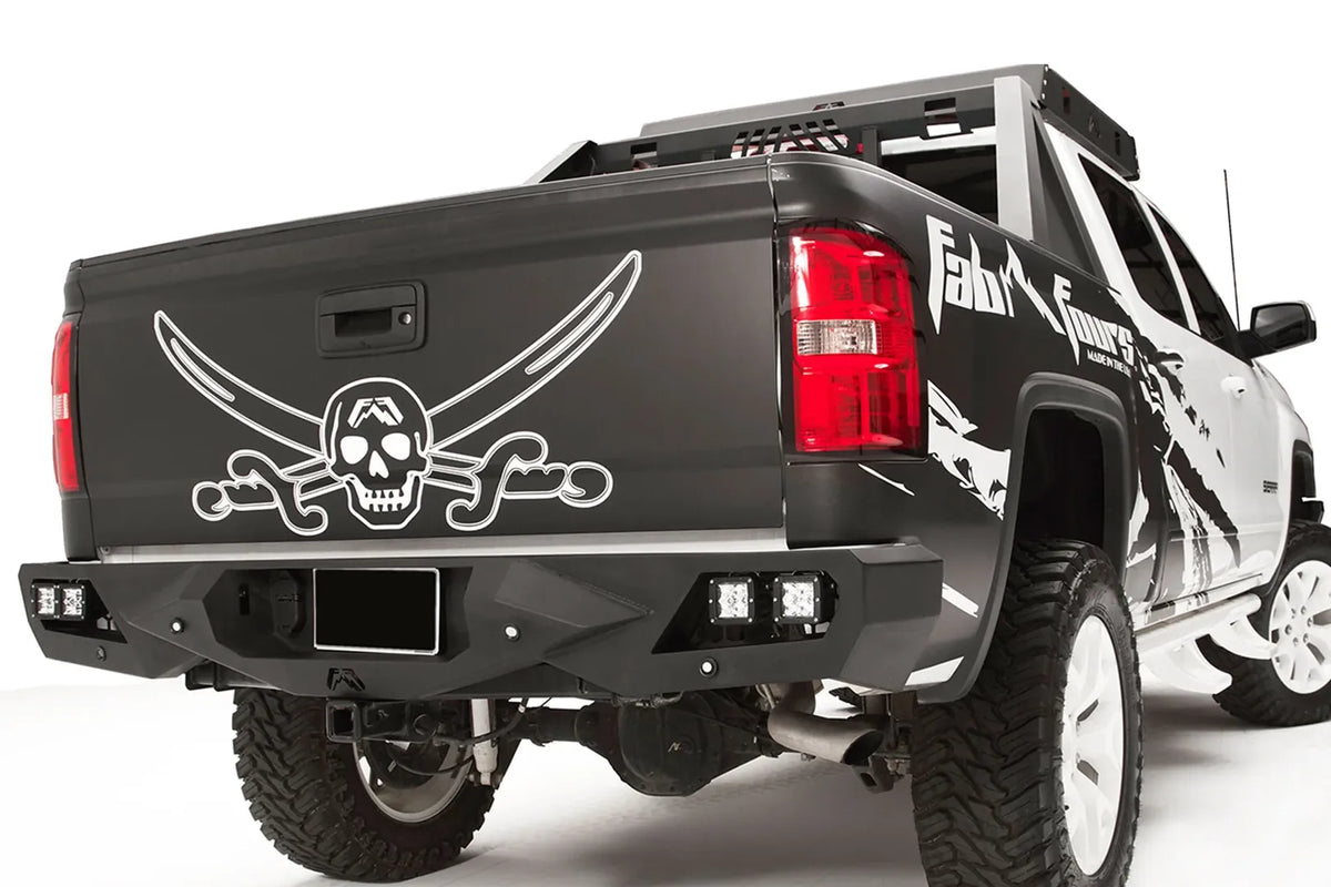 Fab Fours Vengeance rear bumper on a black and white wrapped lifted pickup, rear passenger-side three-quarter view, showing the angular bumper face, cube light pods and wraparound corner