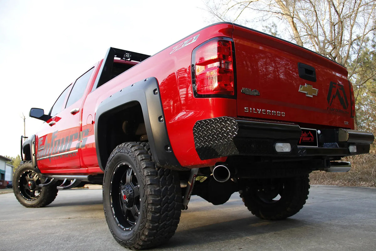 Fab Fours Black Steel Ranch Rear Bumper on a lifted red Chevrolet Silverado 1500 Z71 outdoors, rear driver-side view with tread plate ends, back-up lights and center license plate mount