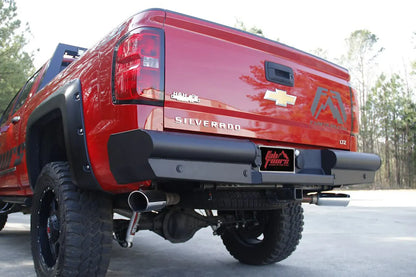 Fab Fours Black Steel Elite Rear Bumper on a lifted red Chevrolet Silverado 1500 outdoors, low rear driver-side view showing the bumper with retained OEM receiver hitch