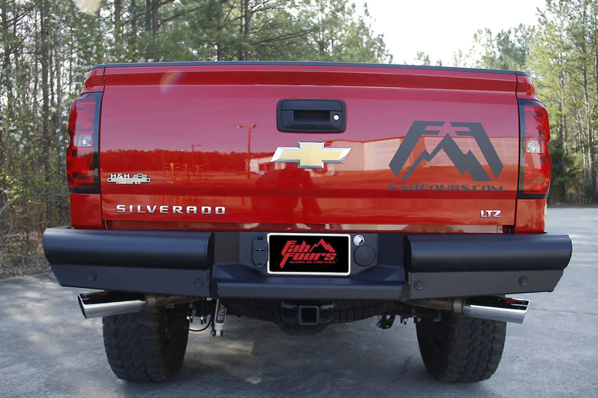 Fab Fours Black Steel Elite Rear Bumper on a red Chevrolet Silverado 1500 LTZ, rear view showing the full-width ranch-style bumper, center plate mount and OEM hitch