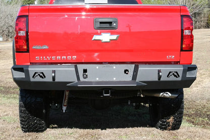 Fab Fours Premium rear bumper on a red lifted Chevrolet Silverado 1500, outdoor straight-on rear view, showing the full-width black steel bumper, logo cutouts and center hitch receiver