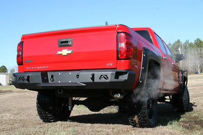 Fab Fours Premium rear bumper on a red lifted Chevrolet Silverado 1500, outdoor rear passenger-side three-quarter view, showing the black steel face, logo cutouts and center hitch receiver