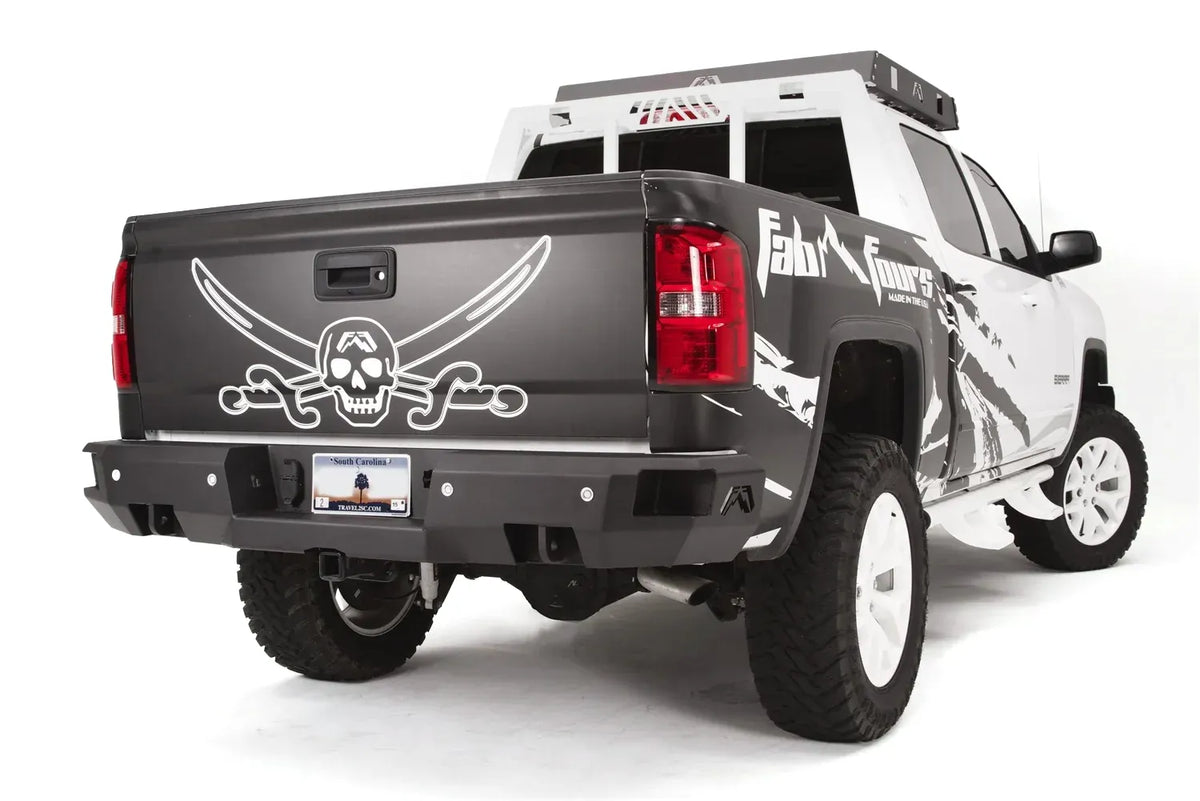 Fab Fours Premium rear bumper on a black and white wrapped lifted pickup, rear passenger-side three-quarter view, showing the black steel face, sensor cutouts and center hitch receiver