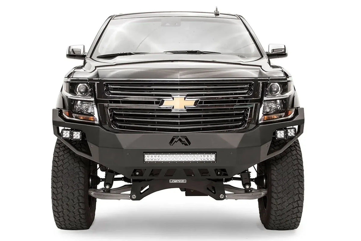 Fab Fours Vengeance front bumper on a black lifted Chevrolet Suburban, straight-on front view, showing the full-width bumper face, center light bar and cube light pods