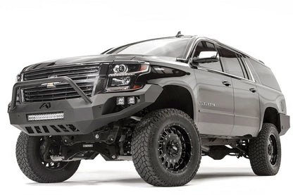 Fab Fours Vengeance front bumper with pre-runner guard on a black lifted Chevrolet Suburban, front driver-side three-quarter view, showing the pre-runner hoop, integrated light bar and slotted skid plate