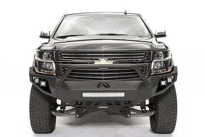 Fab Fours Vengeance front bumper with pre-runner guard on a black lifted Chevrolet Suburban, straight-on front view, showing the tubular pre-runner hoop, center light bar and cube light pods