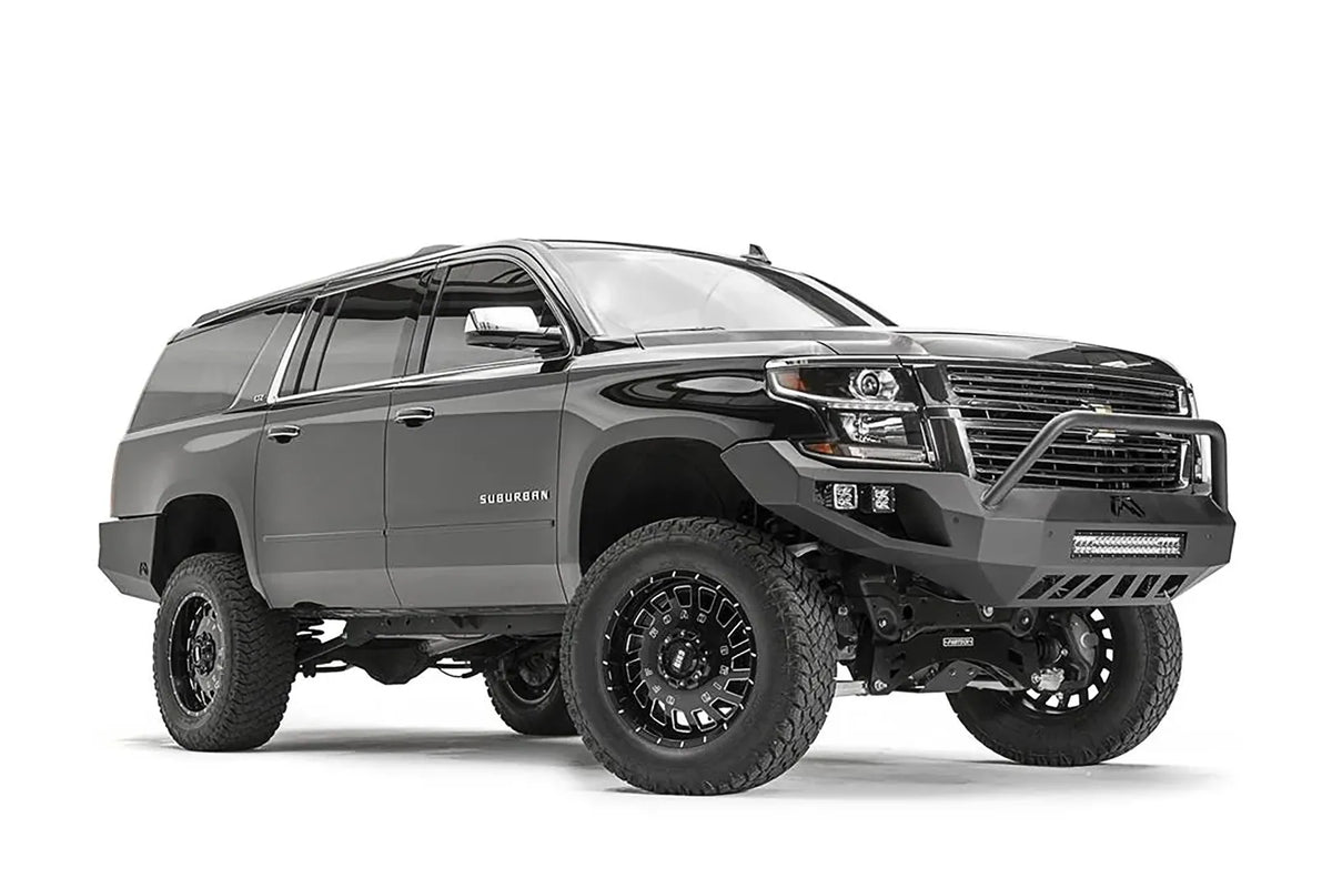 Fab Fours Vengeance front bumper with pre-runner guard on a black lifted Chevrolet Suburban, front passenger-side three-quarter view, showing the tubular pre-runner hoop, integrated light bar and cube light pods