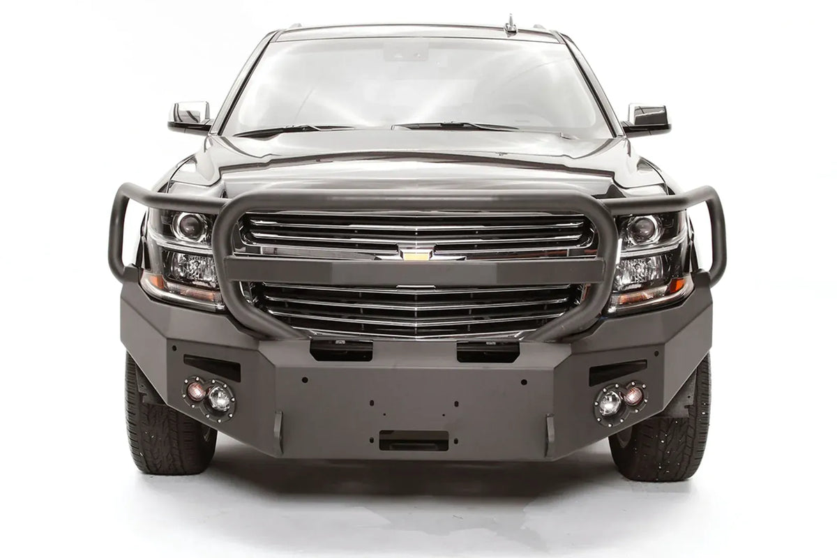 Fab Fours Premium Winch front bumper with full guard on a black Chevrolet Suburban, straight-on front view, showing the tubular full grille guard, winch mount opening and round light cutouts