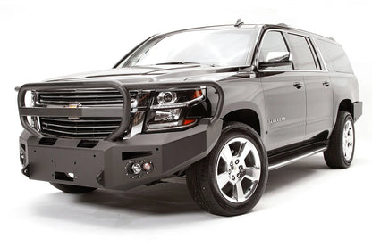 Fab Fours Premium Winch front bumper with full guard on a black Chevrolet Suburban, front driver-side three-quarter view, showing the tubular full grille guard, winch mount and round light cutouts