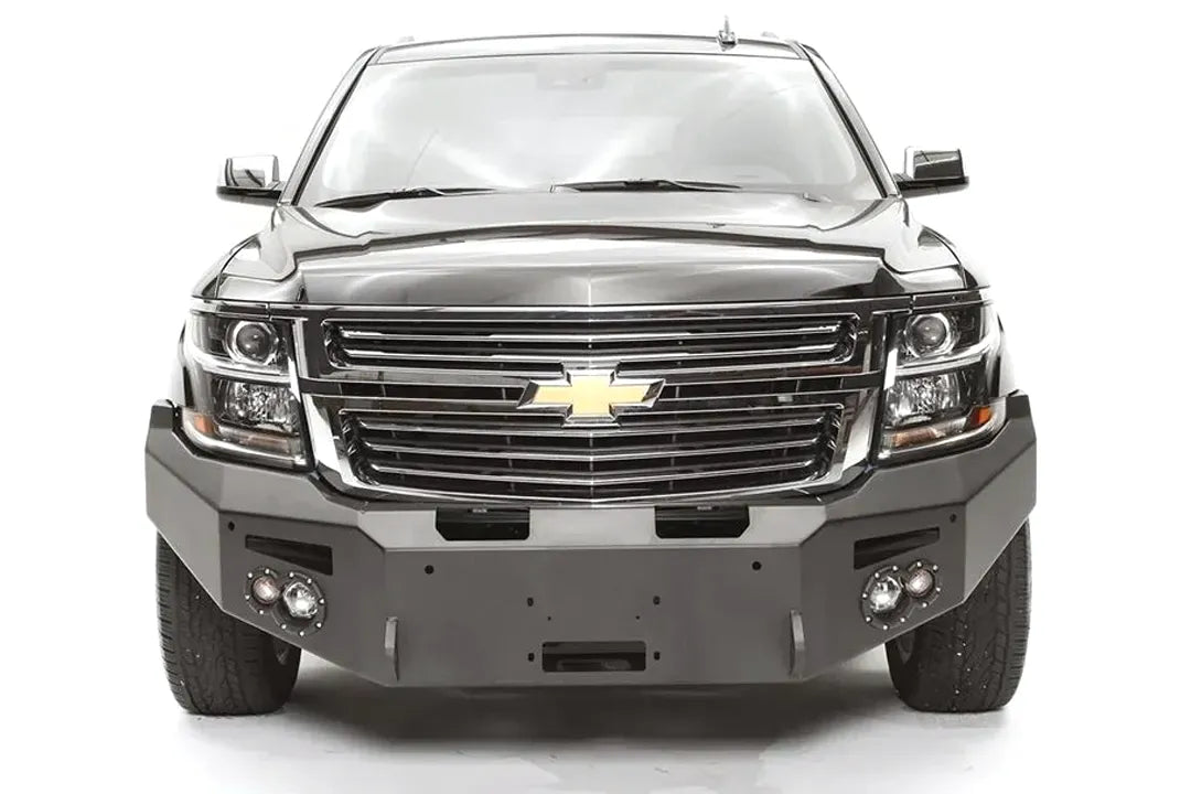 Fab Fours Premium Winch front bumper on a black Chevrolet Suburban, straight-on front view, showing the no-guard design, winch mount opening and round light cutouts