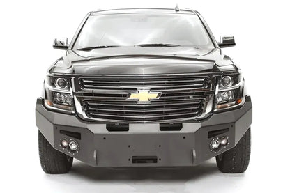 Fab Fours Premium Winch front bumper on a black Chevrolet Suburban, straight-on front view, showing the no-guard design, winch mount opening and round light cutouts