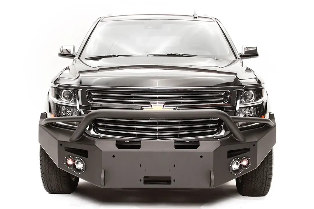 Fab Fours Premium Winch front bumper with pre-runner guard on a black Chevrolet Suburban, straight-on front view, showing the pre-runner hoop, winch mount opening and round light cutouts