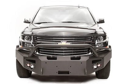 Fab Fours Premium Winch front bumper with pre-runner guard on a black Chevrolet Suburban, straight-on front view, showing the pre-runner hoop, winch mount opening and round light cutouts
