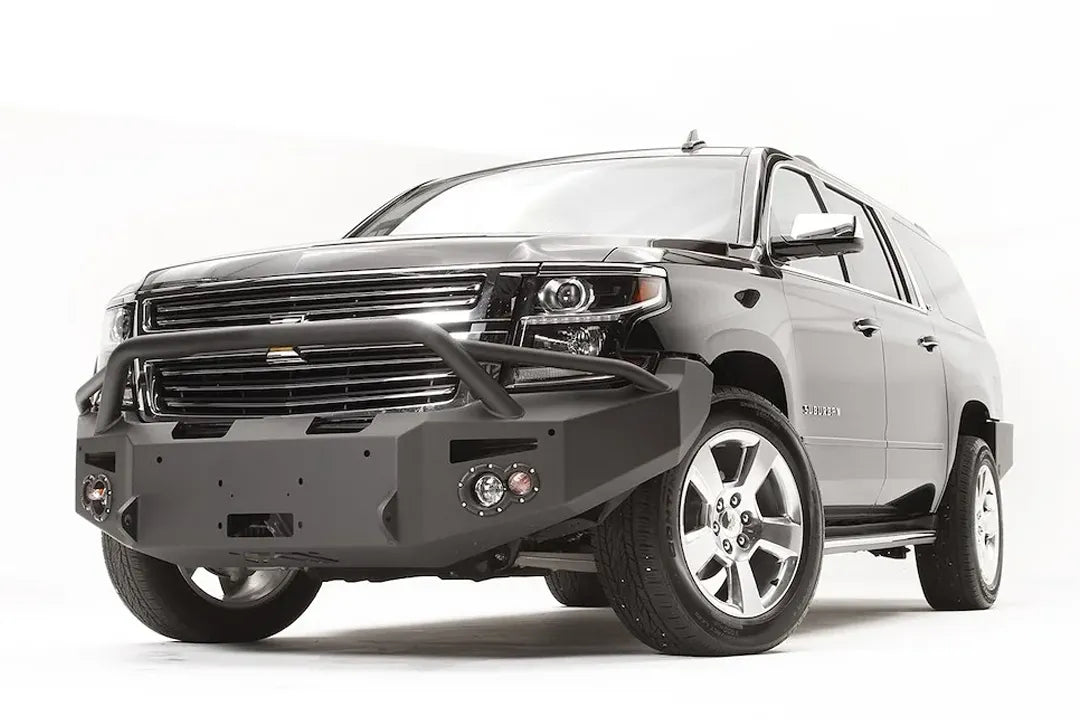 Fab Fours Premium Winch front bumper with pre-runner guard on a black Chevrolet Suburban, front driver-side three-quarter view, showing the tubular pre-runner hoop, winch mount and angled end wing