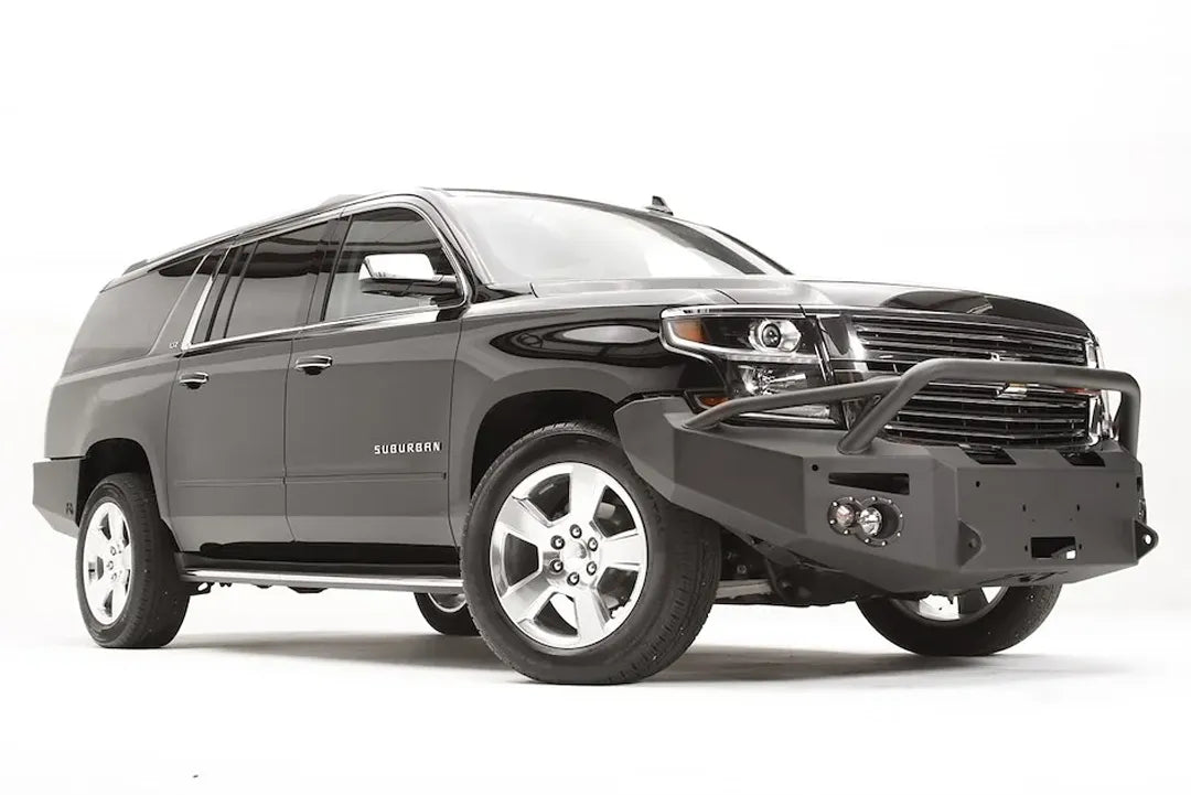 Fab Fours Premium Winch front bumper with pre-runner guard on a black Chevrolet Suburban, front passenger-side three-quarter view, showing the tubular pre-runner hoop, winch mount and round light cutouts