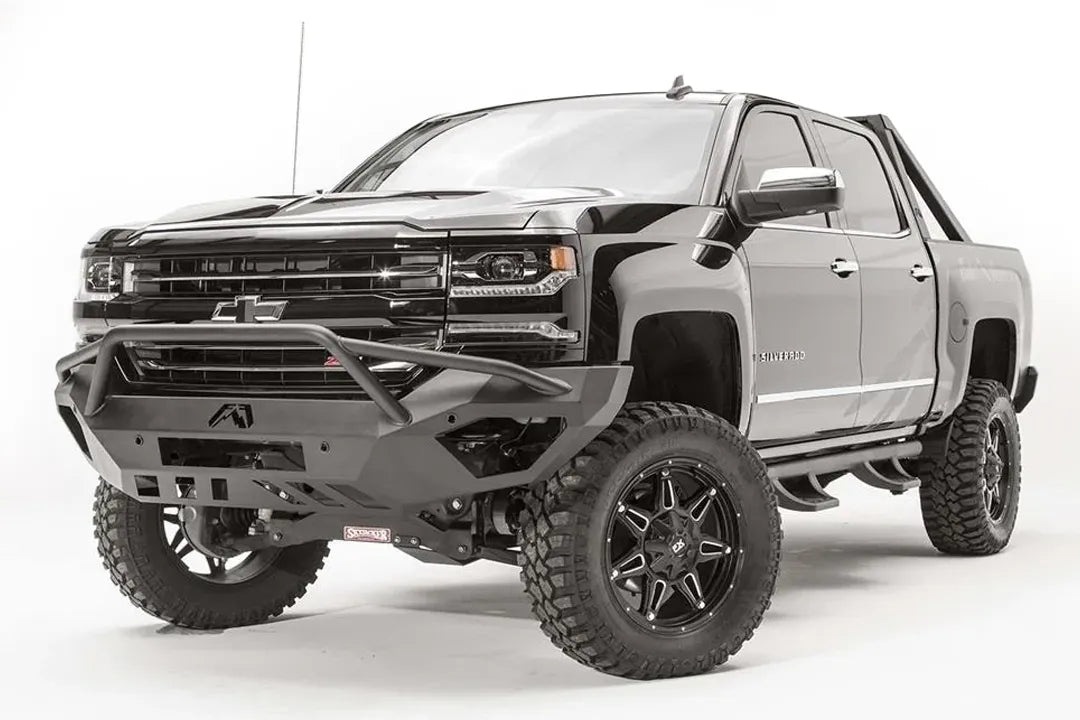 Fab Fours Vengeance front bumper with pre-runner guard on a black lifted Chevrolet Silverado 1500, front driver-side three-quarter view, showing the tubular pre-runner hoop, angular end wings and slotted skid plate