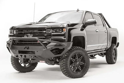Fab Fours Vengeance front bumper with pre-runner guard on a black lifted Chevrolet Silverado 1500, front driver-side three-quarter view, showing the tubular pre-runner hoop, angular end wings and slotted skid plate