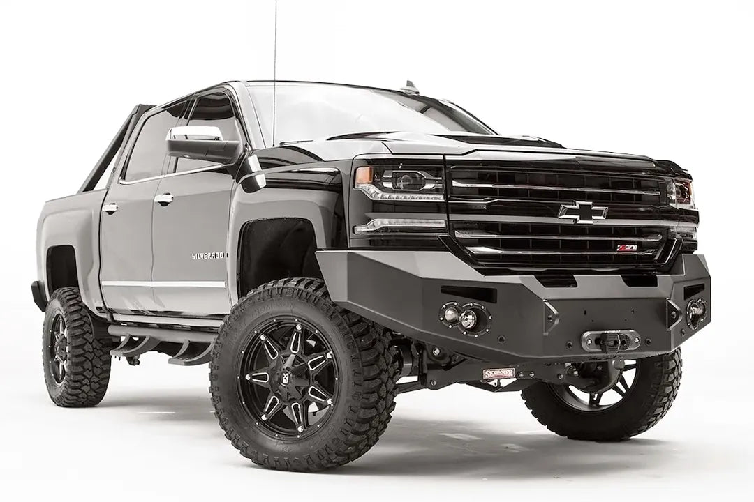Fab Fours Premium front bumper on a black lifted Chevrolet Silverado 1500, front passenger-side three-quarter view, showing the no-guard design, winch mount and round light cutouts