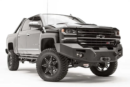 Fab Fours Premium front bumper on a black lifted Chevrolet Silverado 1500, front passenger-side three-quarter view, showing the no-guard design, winch mount and round light cutouts