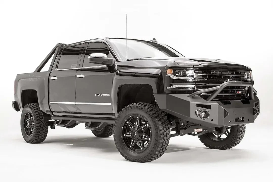 Fab Fours Premium front bumper with pre-runner guard on a black lifted Chevrolet Silverado 1500, front passenger-side three-quarter view, showing the tubular pre-runner hoop, winch mount and round light cutouts