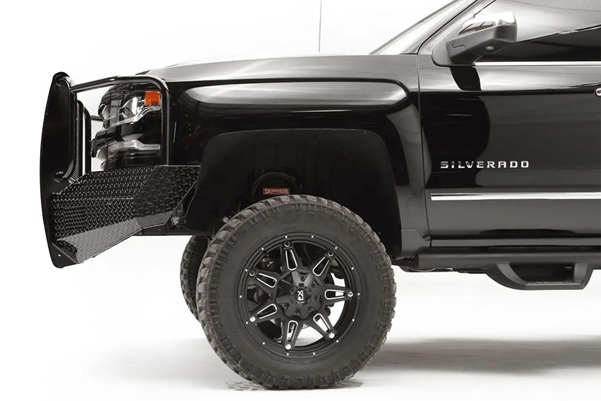 Fab Fours Black Steel front bumper with full guard on a black lifted Chevrolet Silverado 1500, side close-up of the front corner, showing the guard upright, diamond-plate end wing and wheel clearance