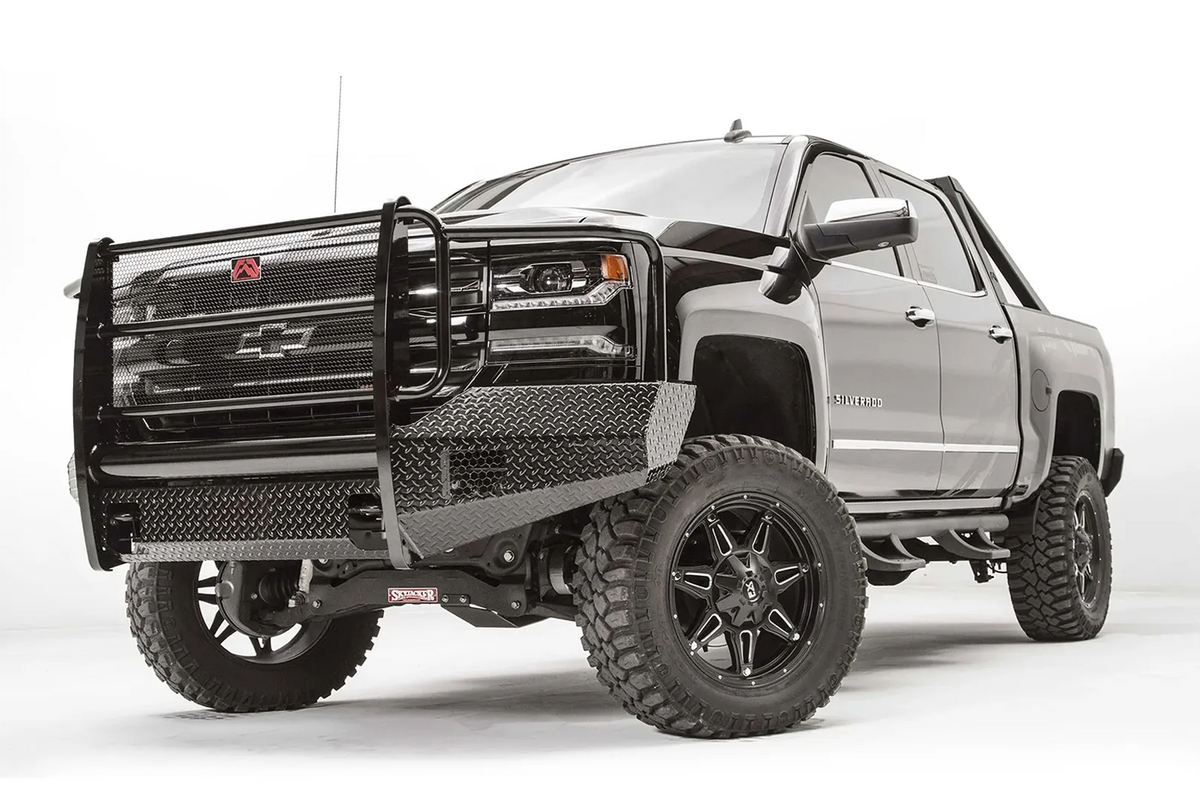 Fab Fours Black Steel front bumper with full guard on a black lifted Chevrolet Silverado 1500, front driver-side three-quarter view, showing the mesh-filled full grille guard, diamond-plate wings and red logo plate