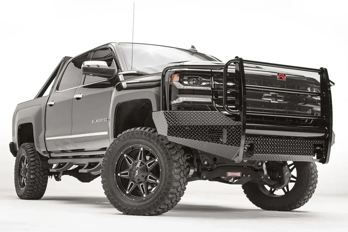 Fab Fours Black Steel front bumper with full guard on a black lifted Chevrolet Silverado 1500, front passenger-side three-quarter view, showing the mesh-filled guard, diamond-plate end wing and red logo plate