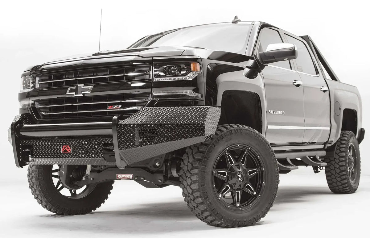 Fab Fours Black Steel front bumper on a black lifted Chevrolet Silverado 1500, front driver-side three-quarter view, showing the no-guard design, diamond-plate wings and red logo plate