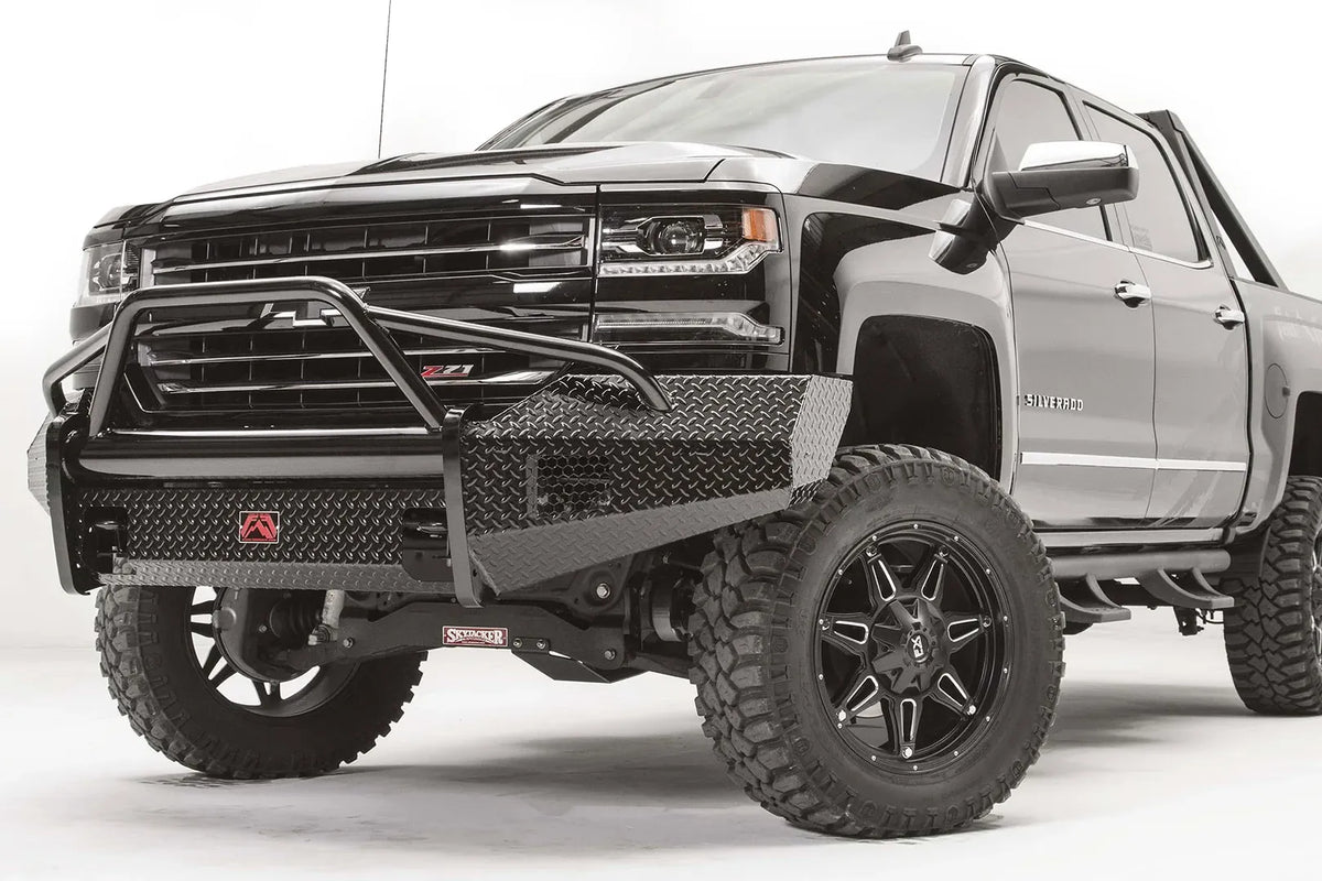 Fab Fours Black Steel front bumper with pre-runner guard on a black Chevrolet Silverado 1500, front driver-side three-quarter view, showing the diamond-plate wings, pre-runner guard tubing, and bumper end clearance