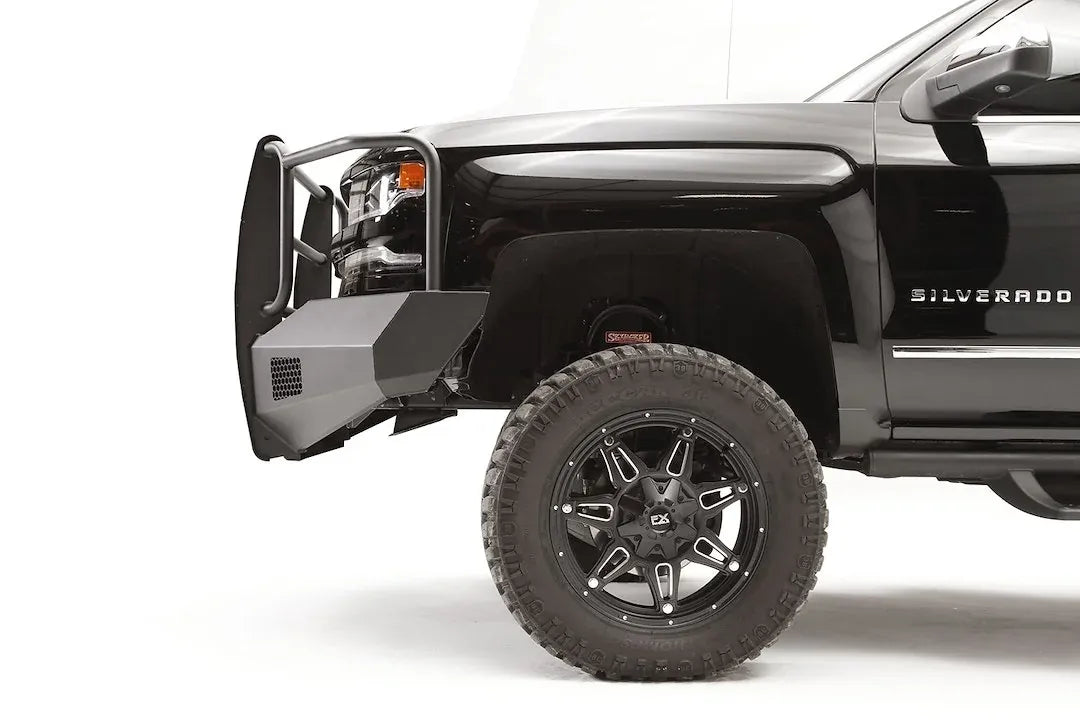 Fab Fours Elite front bumper on a lifted black Chevrolet Silverado 1500, driver-side profile, showing the angular steel bumper end and tubular grille guard ahead of the front wheel
