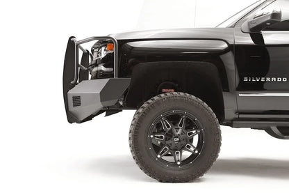 Fab Fours Elite front bumper on a lifted black Chevrolet Silverado 1500, driver-side profile, showing the angular steel bumper end and tubular grille guard ahead of the front wheel