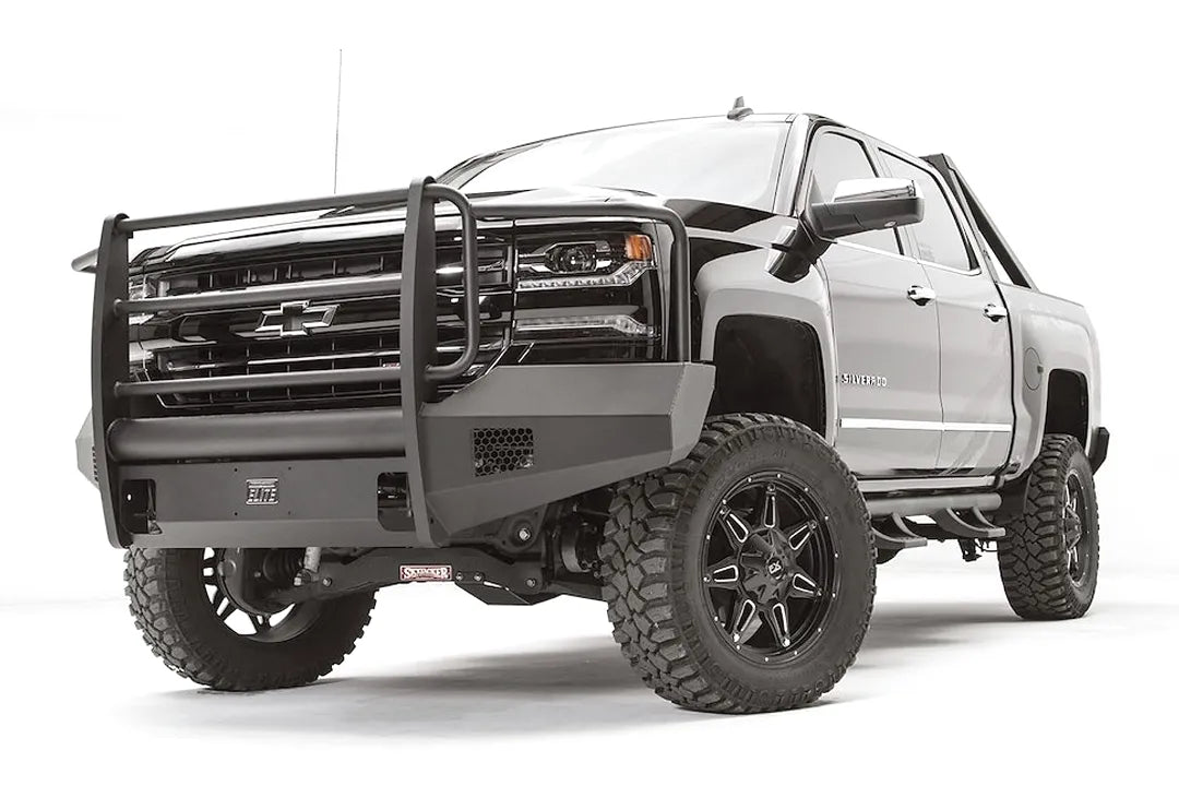 Fab Fours Elite front bumper with grille guard on a lifted gray Chevrolet Silverado 1500, low front passenger-side view, with honeycomb vents and shackle mounts
