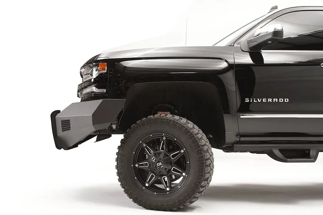 Fab Fours Elite front bumper with pre-runner guard on a lifted black Chevrolet Silverado 1500, driver-side profile, showing the angular steel bumper end ahead of the front wheel