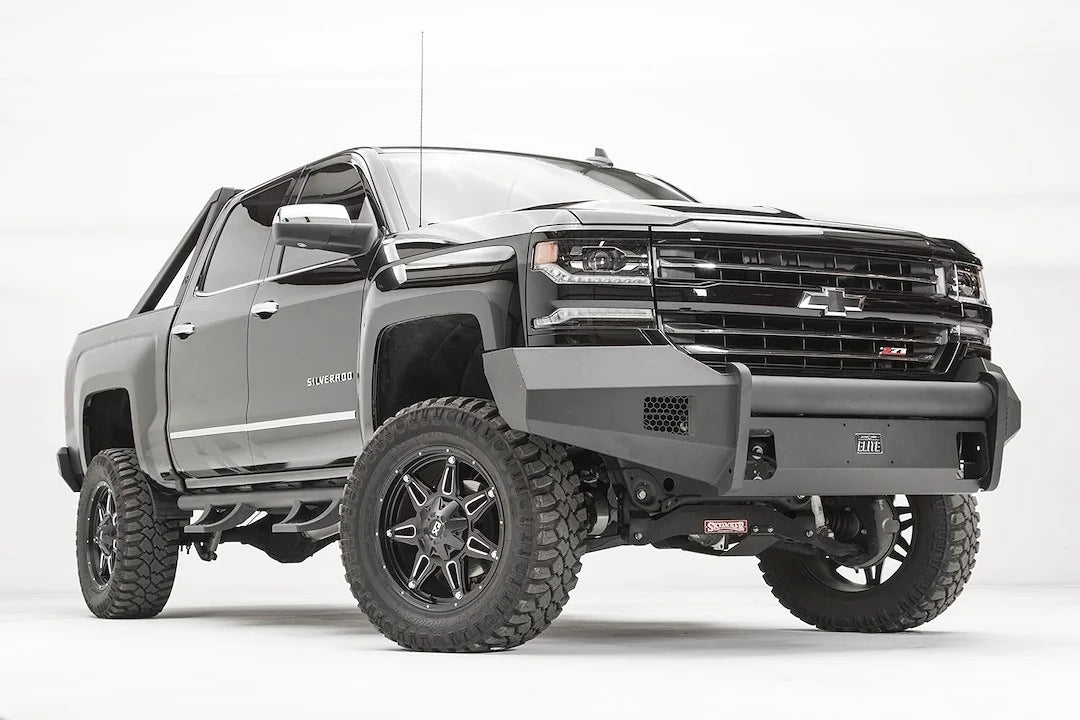 Fab Fours Elite front bumper with pre-runner guard on a lifted Chevrolet Silverado 1500 Z71, low front passenger-side view, with honeycomb vents and matte black steel construction