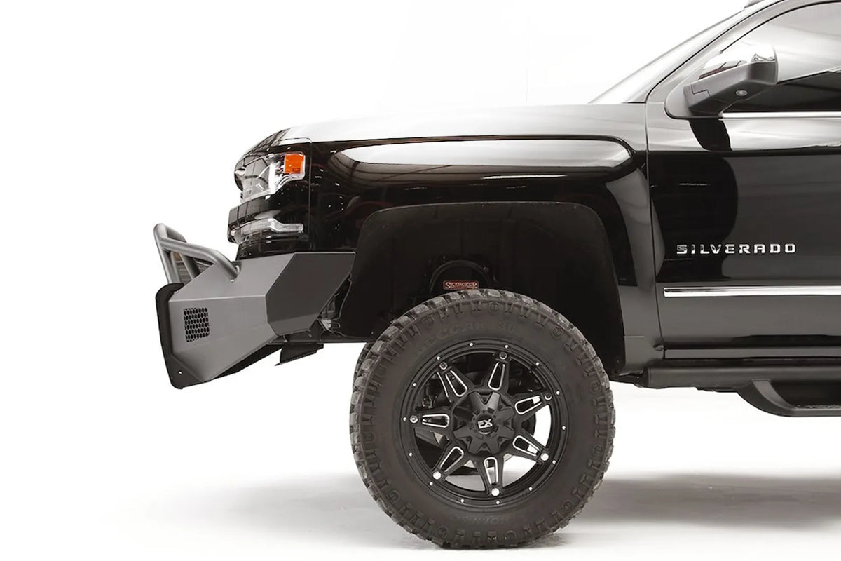 Fab Fours Elite front bumper with pre-runner guard on a lifted black Chevrolet Silverado 1500, driver-side profile, showing the angular bumper end and tubular guard ahead of the front wheel