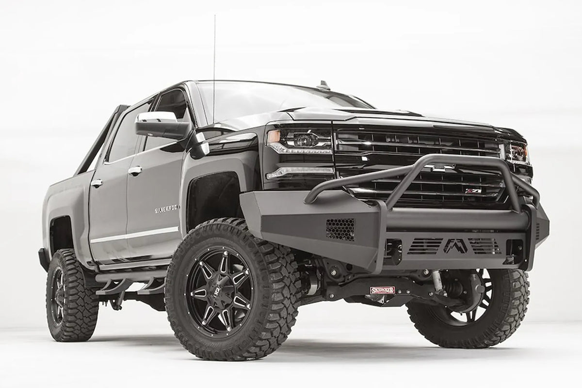 Fab Fours Elite front bumper with pre-runner guard on a lifted Chevrolet Silverado 1500 Z71, low front passenger-side view, with the tubular hoop, honeycomb vents and logo skid plate