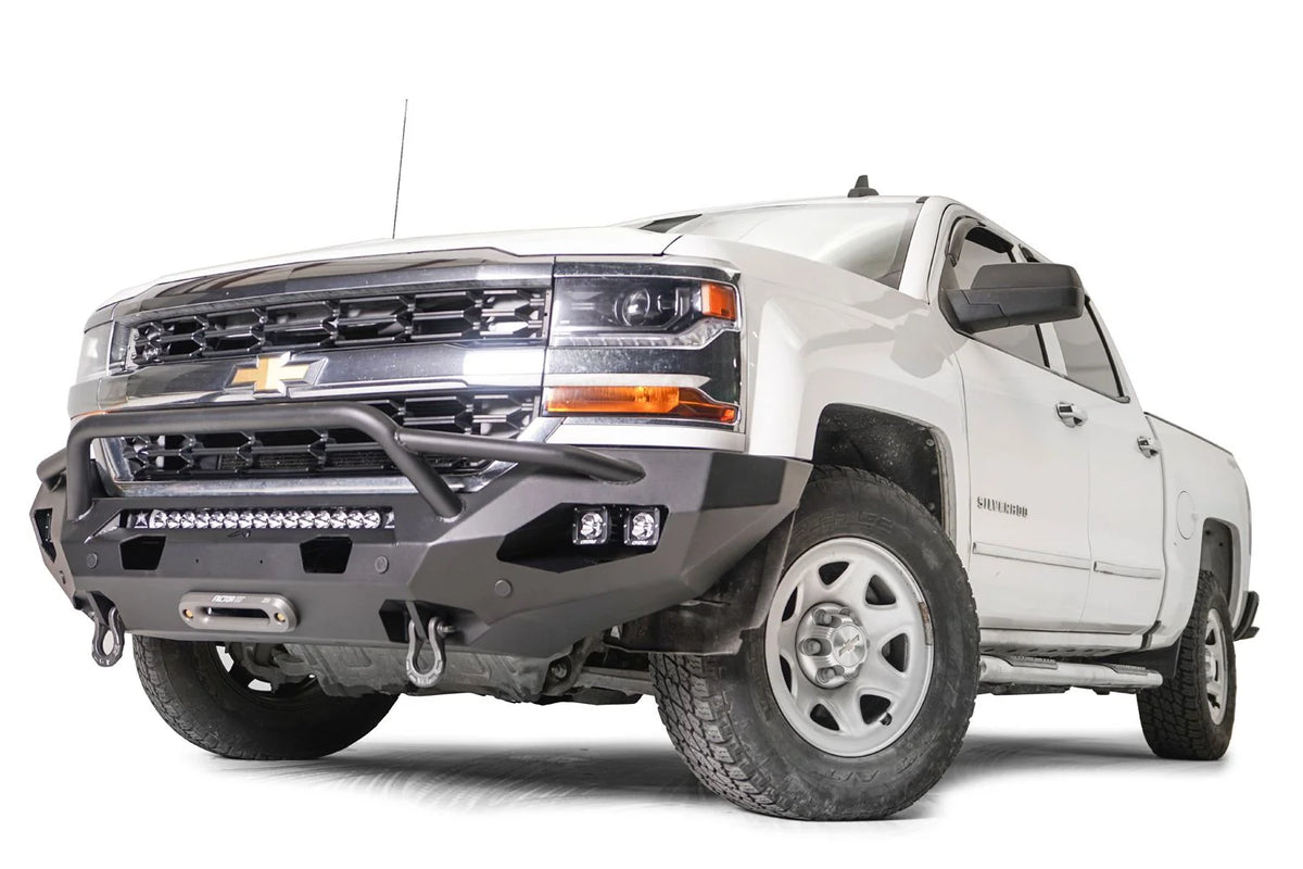Fab Fours Matrix Front Bumper with pre-runner guard on a white Chevrolet Silverado 1500, front driver-side view, with the tubular guard, center light bar, side cube lights and integrated D-ring mounts