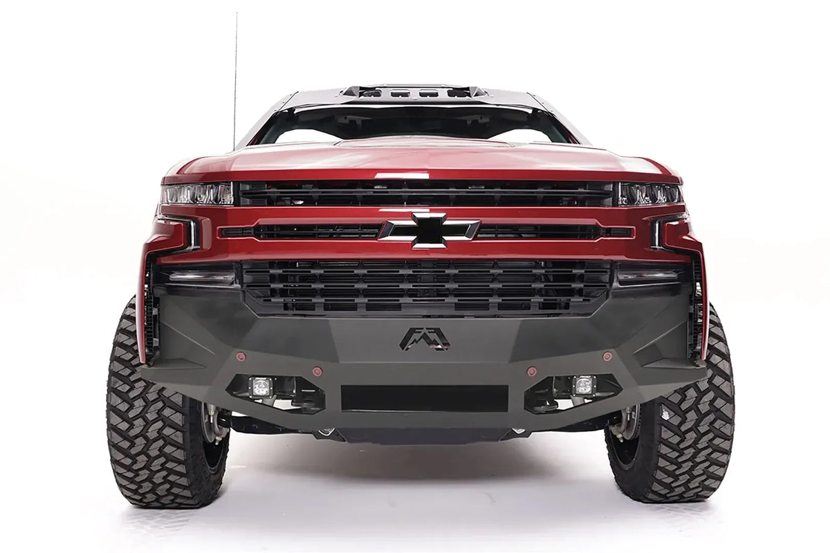 Fab Fours Vengeance front bumper on a red Chevrolet Silverado 1500, straight-on front view, showing the angular plated face, center Fab Fours logo, and integrated light pods
