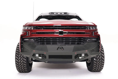 Fab Fours Vengeance front bumper on a red Chevrolet Silverado 1500, straight-on front view, showing the angular plated face, center Fab Fours logo, and integrated light pods