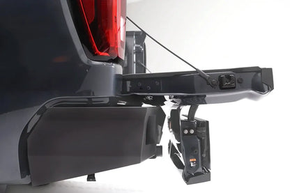 Fab Fours Vengeance rear bumper on a gray GMC Sierra 1500, close-up of the tailgate corner and bumper mount, showing the mounting bracket, hitch area, and bumper end