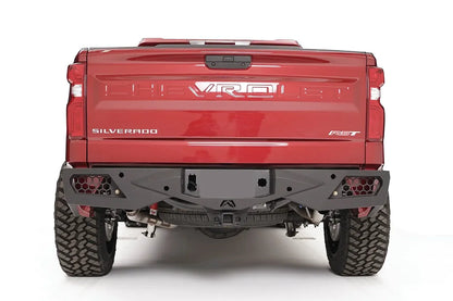 Fab Fours Vengeance rear bumper on a red Chevrolet Silverado 1500, straight-on rear view, showing the honeycomb light pockets, center license plate recess, and hitch receiver
