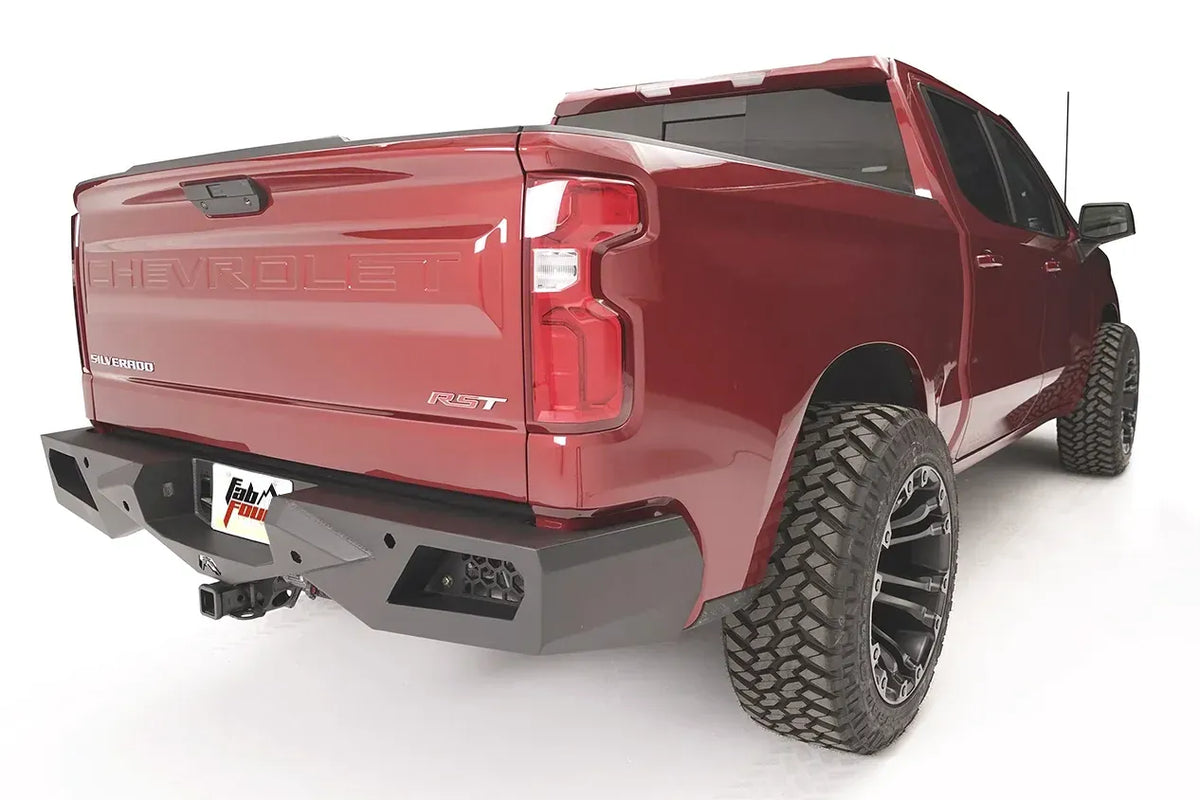 Fab Fours Vengeance rear bumper on a red Chevrolet Silverado 1500, rear three-quarter view, showing the angular bumper end, honeycomb light pocket, and hitch receiver